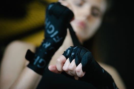 Soft focus of crop woman bandaging hands and wrists with boxing wraps on blurred background