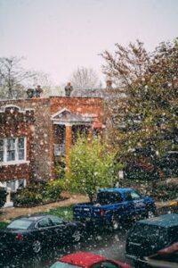 A snowy street in Chicago featuring parked cars, homes, and falling snowflakes.