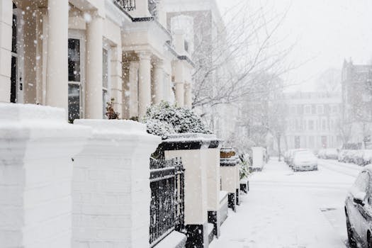 A charming snowy street scene with residential buildings in London.