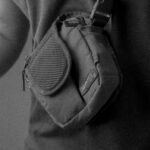 Monochrome close-up of a person wearing a compact shoulder bag.