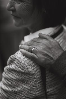 Close-up of an elderly couple showing warmth and connection. One hand rests gently on a shoulder.