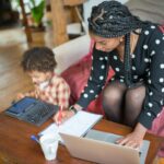 Mother multitasking with work and child at home, showcasing modern parenting.