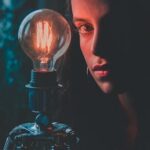A thoughtful woman beside an illuminated Edison bulb creating a dramatic mood.